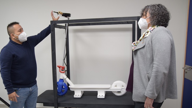 Gustavo Salcedo muestra a la rectora, Beatriz Miguel, el simulador de conducci&oacute;n de patinete el&eacute;ctrico, y &Aacute;lvaro Maci&aacute;n y Lola Ojados ense&ntilde;&aacute;ndole la fuente de sincronizaci&oacute;n lum&iacute;nica
