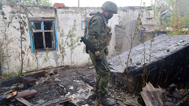Un soldado ucranio revisa las ruinas de una vivienda destrozada por la artiller&iacute;a