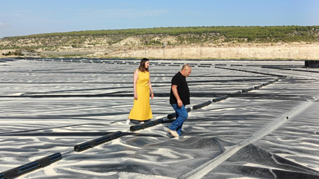 Imagen de la consejera junto a uno de los beneficiarios de las ayudas con las que ha cubierto el embales de agua sobre el que caminan. | Foto. GOBIERNO REGIONAL Imagen de la consejera junto a uno de los beneficiarios de las ayudas con las que ha cubierto el embales de agua sobre el que caminan. | Foto. GOBIERNO REGIONAL