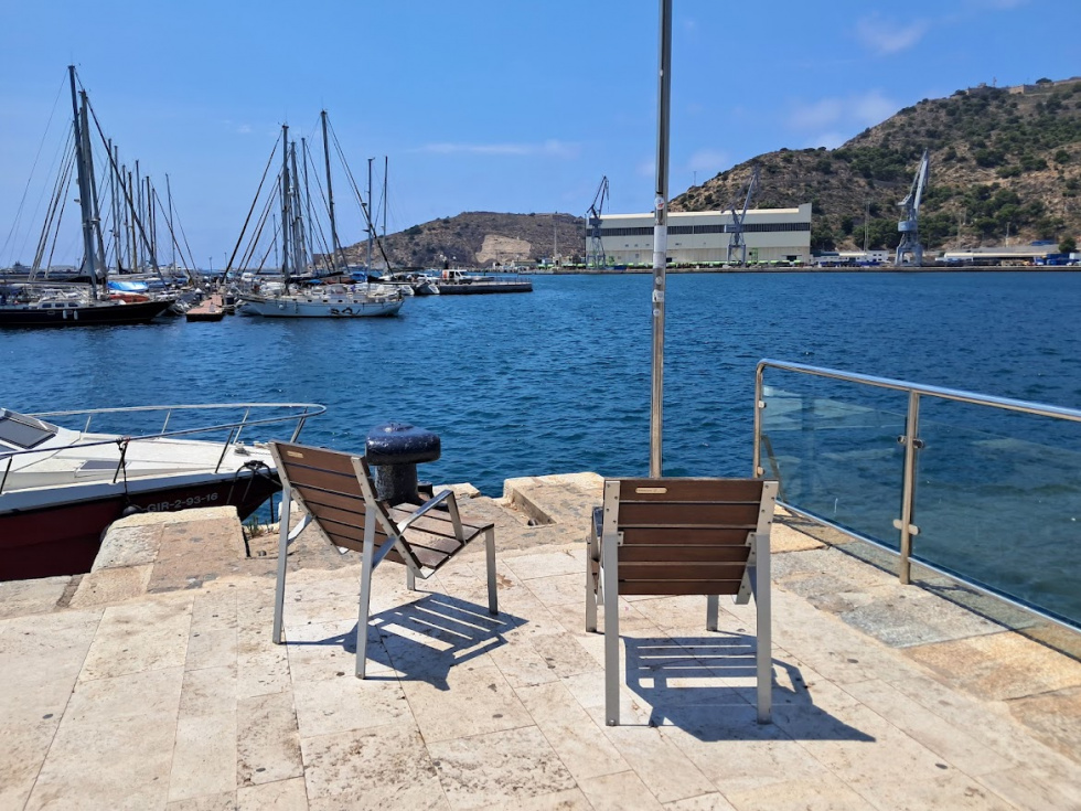 Sillones frente a Navantia, pensados para contemplar el puerto. A las 13:15h del 1 de julio de 2026, ninguno de los dos tiene ocupante