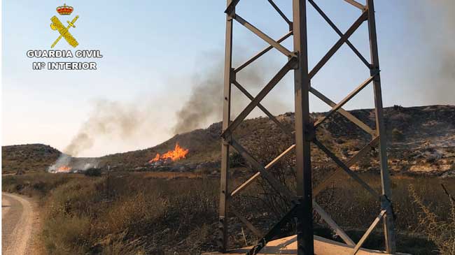 Torre el&eacute;ctrica y al fondo el fuego que se origin&oacute;