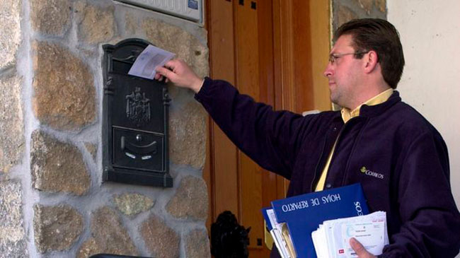 Un cartero de Correos realizando la entrega diaria de correspondencia.
