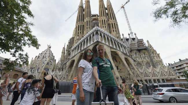 Turistas fotografi&aacute;ndose frente a la Sagrada Familia, en Barcelona